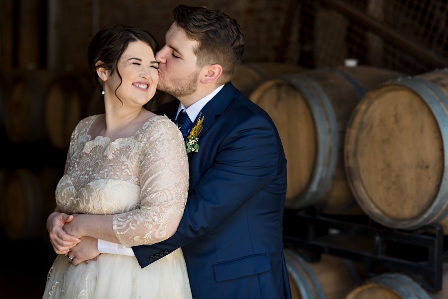 A wedding couple in front of barrels of beer.